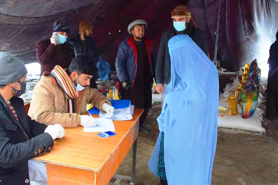 A woman beneficiary of Dastarkhwan-e Meli is being checked for her name in the list